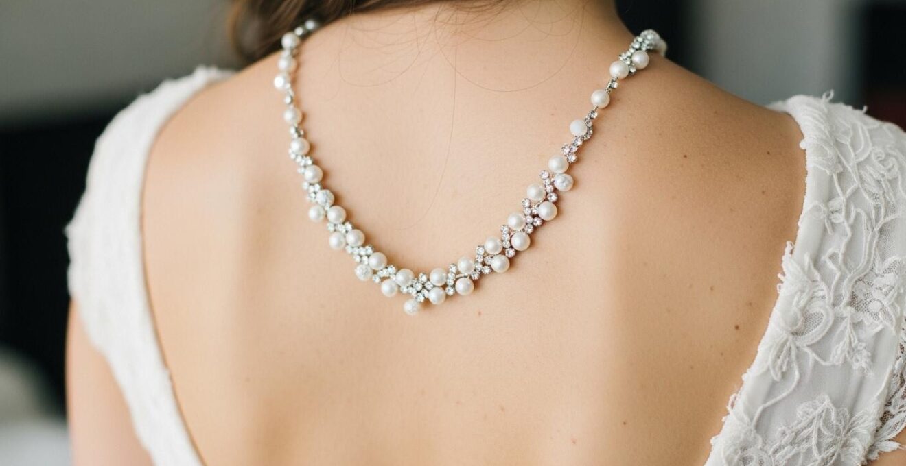 Photographie montrant un collier de dos en perles et cristaux sur une robe dos nu de mariée